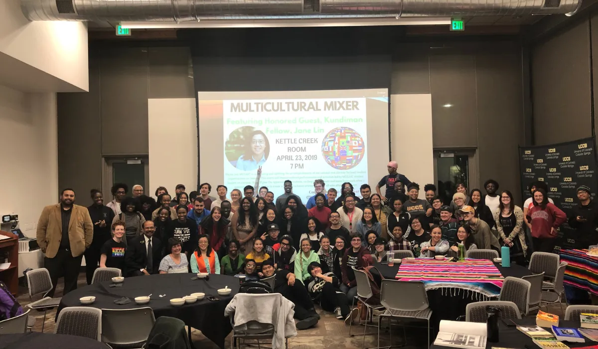 Photo of students posing in front of a screen that states "Multicultural Mixer"