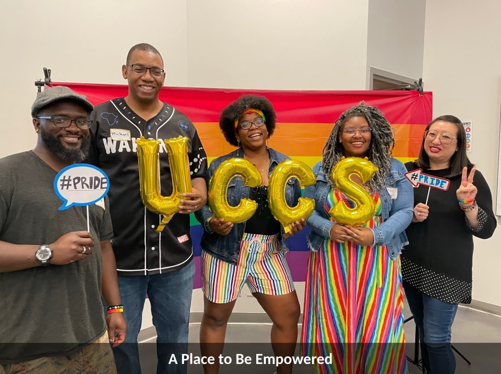 Photo of UCCS staff, faculty, and alumni at PRIDE holding gold balloons that spell UCCS
